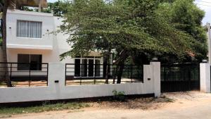 a fence in front of a house with a tree at Harry Inn in Negombo