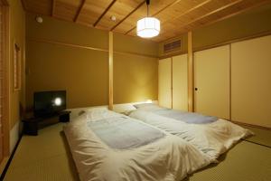 a bedroom with two beds and a tv in it at HANARE KYOTO Onyado Hasegawa in Kyoto