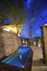 a swimming pool in front of a stone wall at Santa Marina Guesthouse in Kato Loutraki