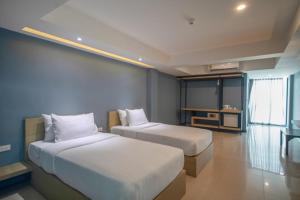 a hotel room with two beds and a television at Nora LakeView in Chaweng