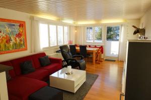 a living room with a red couch and a table at Chalet Windegg - CharmingStay in Flumserberg