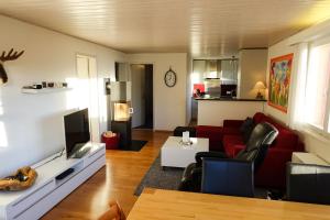 a living room with a red couch and a tv at Chalet Windegg - CharmingStay in Flumserberg