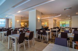 un comedor con mesas y sillas blancas en Hotel ***NAT Sarbinowo, en Sarbinowo