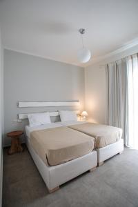 a white bedroom with a large bed and a window at Sweet Home Naxos in Naxos Chora