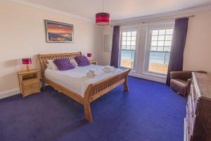 a bedroom with a bed and a couch and windows at Promenade Apartment with own Beach Hut in Totland