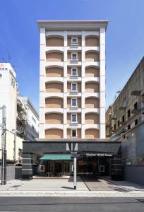 a tall white building with a sign in front of it at Welina Hotel Premier Shinsaibashi in Osaka
