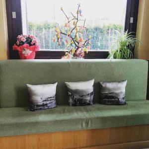 a green couch with three pillows in front of a window at Hotel Fioroni in Bellagio