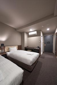 大阪市にあるWelina Hotel Premier Shinsaibashiのベッド2台とデスクが備わるホテルルームです。