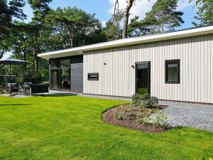 a white house with a patio and a lawn at Chic Forest Lodge with Sauna in Markelo +32 photos