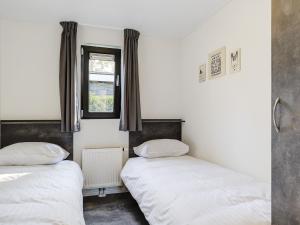 twee bedden in een kamer met een raam bij Relaxing Forest Hideaway in Markelo