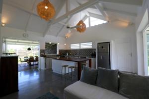 sala de estar y cocina con sofá y mesa en Kaza Blanka - Kaze Tropicale***** - Saint Leu - Réunion, en Saint-Leu