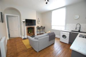 a living room with a gray couch and a kitchen at Modern One Bed Apartment, by Kipz City Centre Chester - Amazing Location & Quiet! in Chester