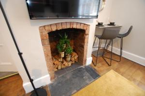 a living room with a brick fireplace with a tv on top at City Centre 1 Bed Apartment - Modern & Bright in Chester