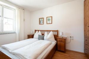 a bedroom with a bed with white sheets and a window at Appartements Kaserbacher in Salzburg
