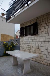 a white bench sitting in front of a brick wall at Apartman Aurora in Poreč