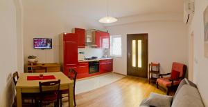 a living room with a table and a kitchen with red cabinets at Apartman Aurora in Poreč