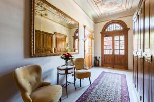 pasillo con mesa, 2 sillas y espejo en Villa Savioli Room & Breakfast, en Bolonia