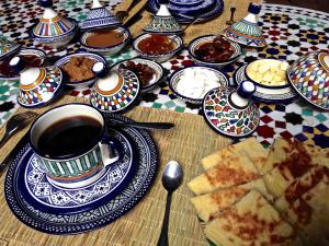 una mesa con platos de comida y una taza de café en Riad Toyour- Riad of birds, en Fez