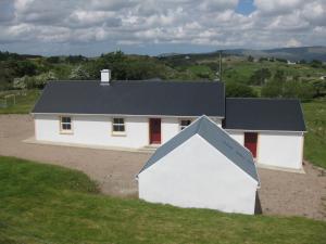 a white house with a black roof on a field at Willies cottage in Donegal
