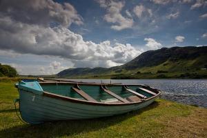 ein Boot auf dem Gras neben dem Wasser in der Unterkunft Willies cottage in Donegal