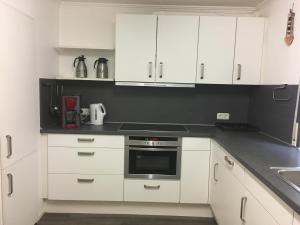 a kitchen with white cabinets and a black counter top at Sauerland vakantiehuisje in Diemelsee