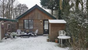 a cabin with chairs and a table in the snow at Vakantiehuis Duin Bos en Zee in Schoorl +8 photos