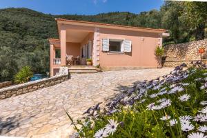 a house with a stone driveway and flowers at The Olive Grove Cottage by Konnect - 2,5km from Ipsos in Ýpsos