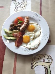 a plate of breakfast food with eggs sausage and vegetables at Asante Guest House in Vanderbijlpark