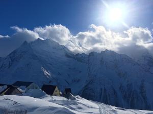 a snow covered mountain with the sun in the sky at Apartment in ZHK Sputnik in Dombay