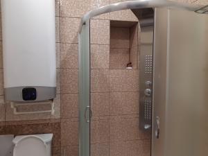 a bathroom with a shower with a toilet and a glass door at Apartment in ZHK Sputnik in Dombay