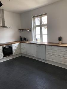 cocina grande con armarios blancos y ventana en Kildegaarden en Kokkedal