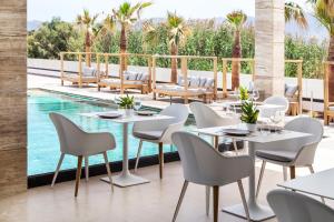 a dining area with chairs, tables, chairs and umbrellas at Lango Design Hotel & Spa, Adults Only in Kos