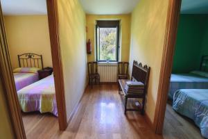 Habitación con 2 camas, 2 sillas y espejo. en Casa Rural El Secreto del Bosque, en La Omañuela