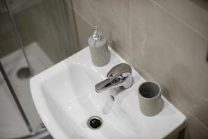 a bathroom sink with a faucet and a cup on it at APARTAMENT PRZYTULNY in Kielce