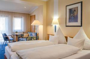ein Hotelzimmer mit 2 Betten und einem Stuhl in der Unterkunft Hotel Lamm in Heimbuchenthal