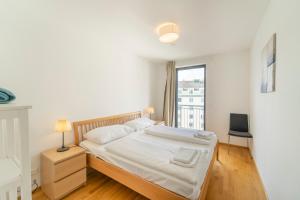 a white bedroom with a bed and a window at easy flat Margareten Apartments in Vienna