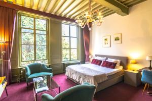 een slaapkamer met een bed en een aantal stoelen en ramen bij Hotel aan de Dam in Middelburg