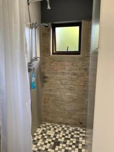 a bathroom with a shower with a window and a tile floor at 15 Arbour Road Apartment in George