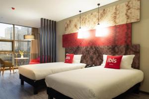 two beds in a hotel room with red pillows at Ibis Xi'an South Gate in Xi'an