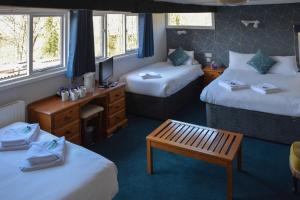 a room with two beds and a table and a bench at Llanerch Inn in Llandrindod Wells +38 photos