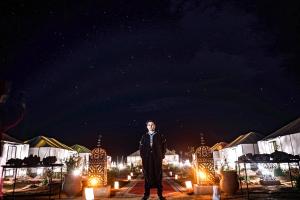 a man standing on a stage at night at Sahara Majestic Luxury Camp in Merzouga
