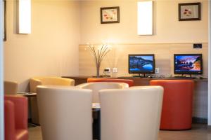 a waiting room with chairs and two monitors at Ace Hôtel Paris Marne La Vallée in Bailly-Romainvilliers