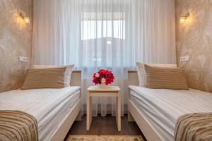 een slaapkamer met 2 bedden en een vaas met bloemen op een tafel bij Kesminta Šalčininkai in Šalčininkai