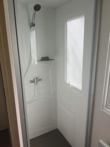 una ducha con una puerta de cristal junto a una ventana en Boscamping Appelscha, en Appelscha
