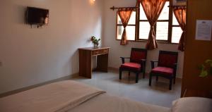 a bedroom with a bed and two chairs and a desk at Hotel Kismat Mahal in Calangute