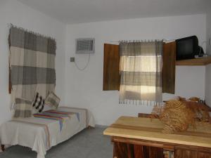 a bedroom with a bed and a table and a tv at Sol da Onda Pousada e Flats in Barra Grande