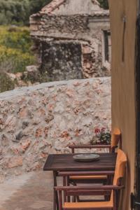a wooden table and chairs in front of a stone wall at La Casa Di Nonna in Koríthion