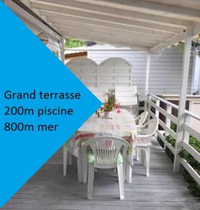 una mesa blanca y sillas en un porche en mobilhome 500m mer camping LA CARABASSE, en Vias