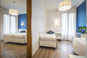 リニャーノ・サッビアドーロにあるHotel Capanna d'Oroのベッド2台と鏡が備わるホテルルームです。