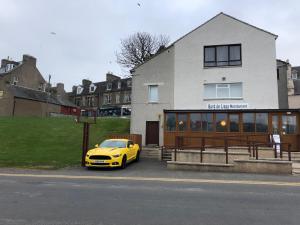 a yellow car parked in front of a building at BORD DE L’EAU APARTMENT in Wick